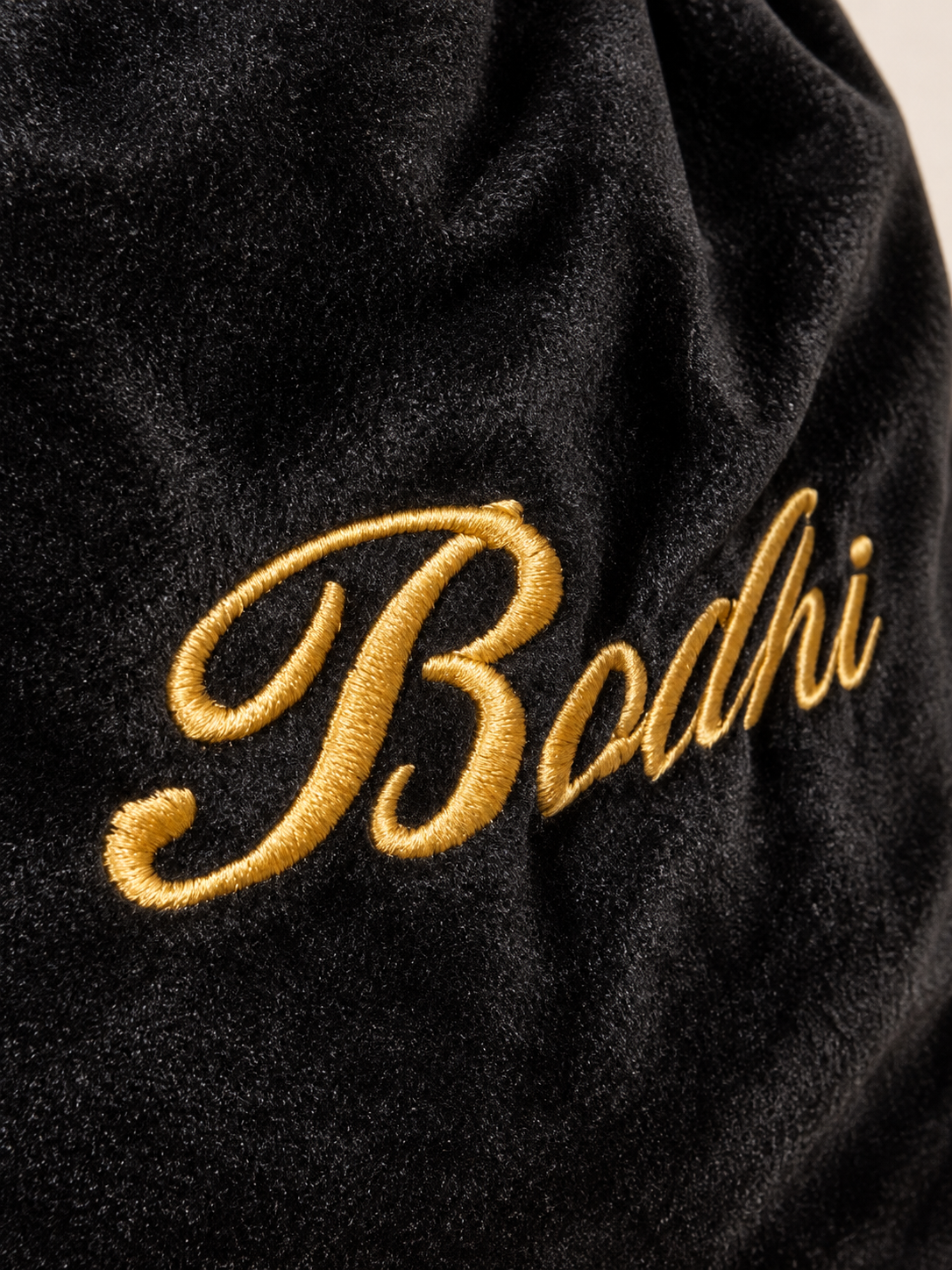 Detail van gouden geborduurde naam op zwarte velvet stof