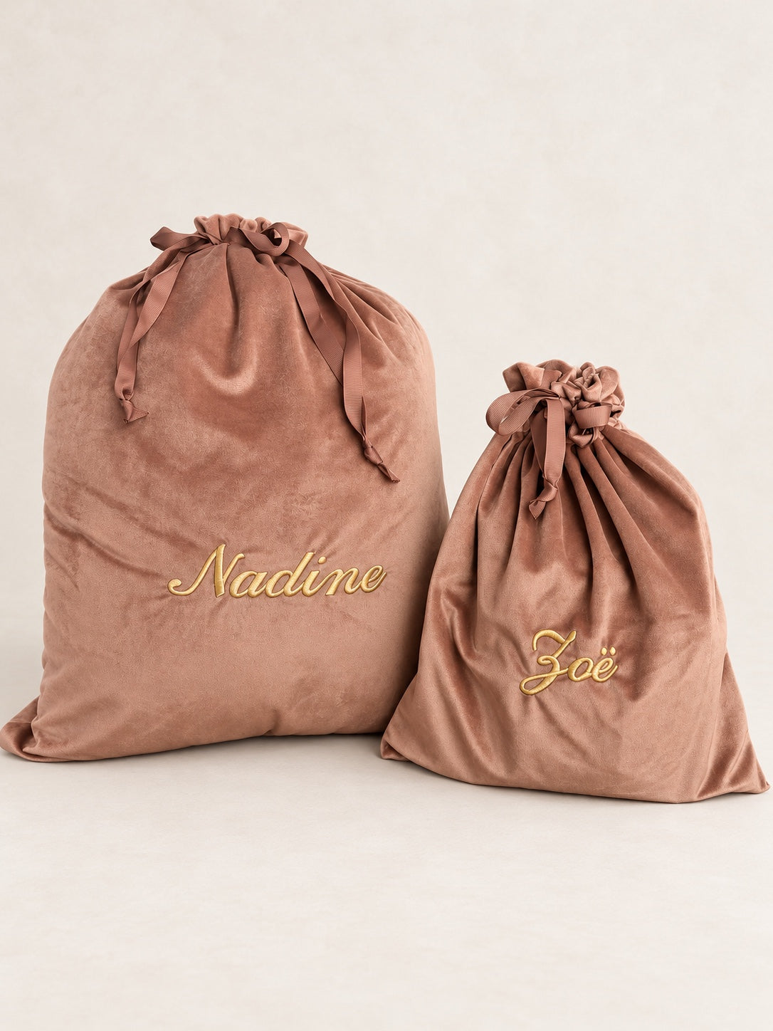 Twee gepersonaliseerde oudroze velvet cadeauzakken in verschillende maten